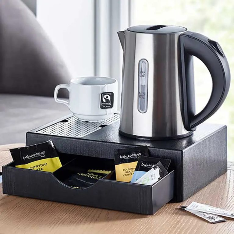 Hotels, Holiday Parks and Airbnbs A kettle with a cup and a drawer containing various tea bags on a table.
